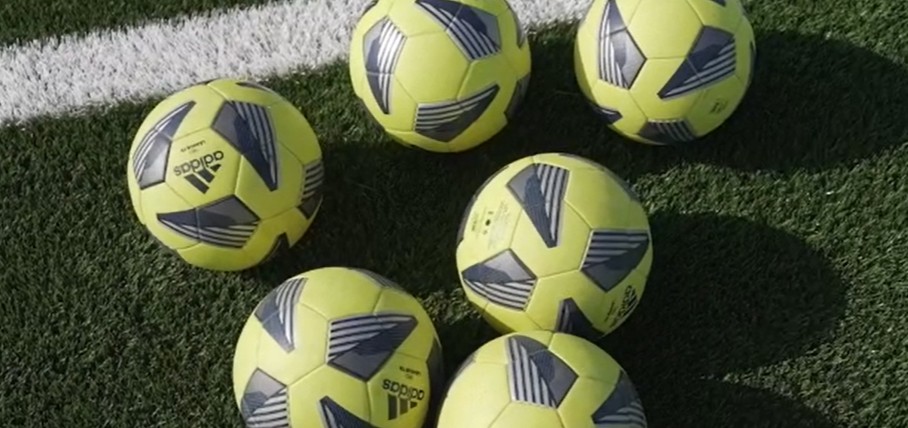 Balones de fútbol sobre el césped de un campo universitario en Estados Unidos